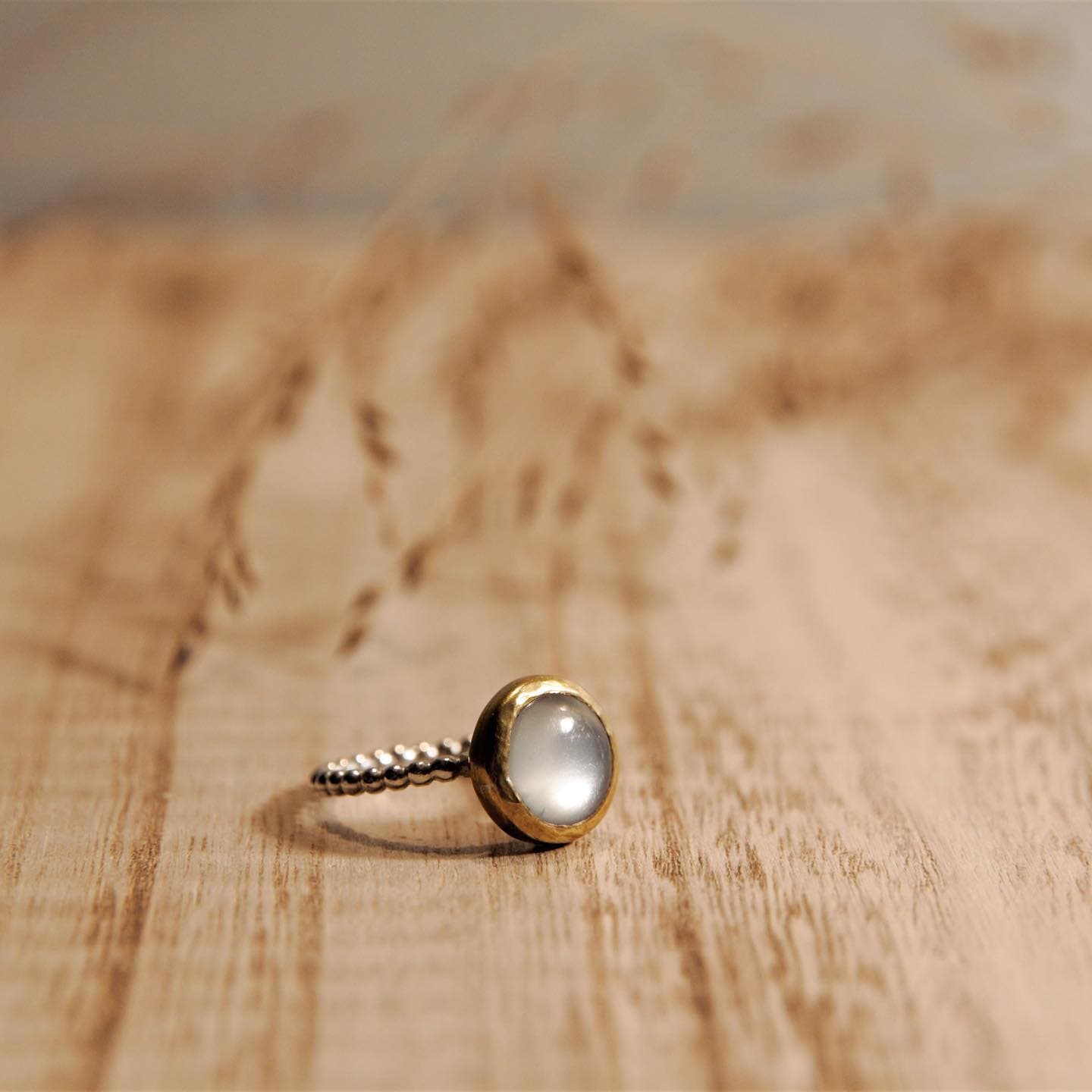 Gouden ring met kleine parel op houten ondergrond