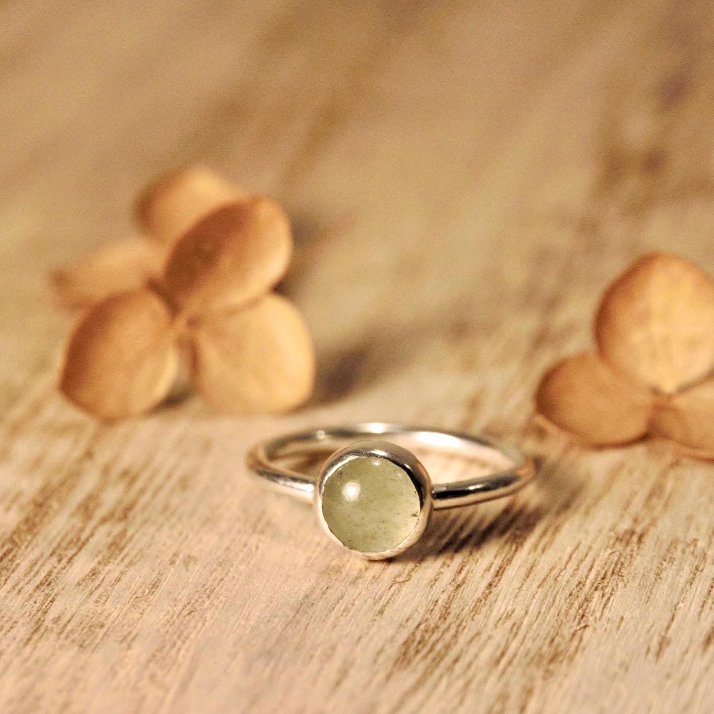 Gouden ring met heldere steen op hout bij gele bloemen