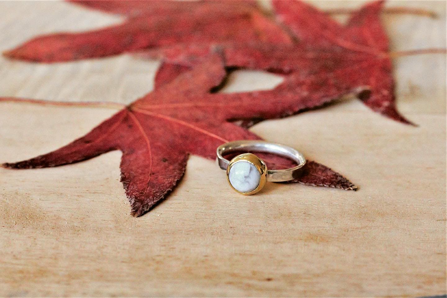 Gouden ring met heldere steen op herfstblad