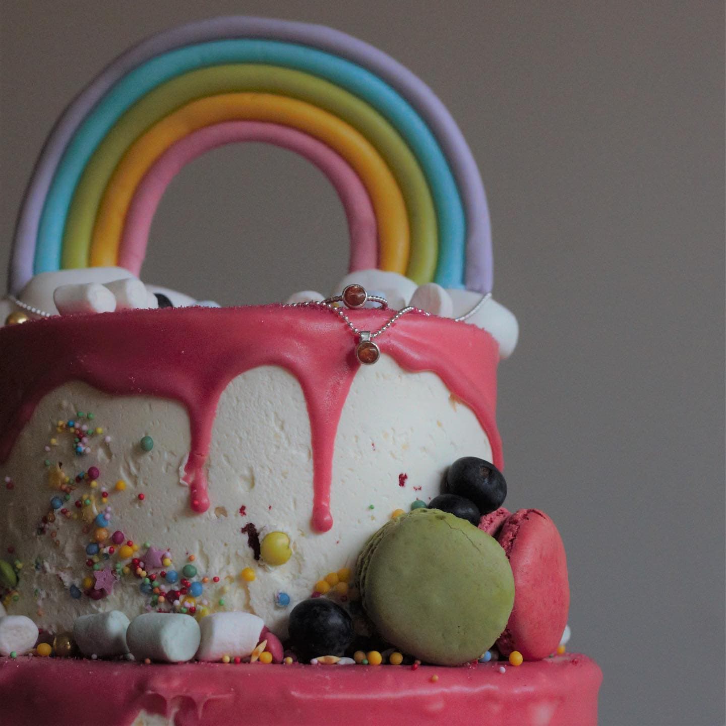 Zilveren halsketting op taart met regenboogdecoratie