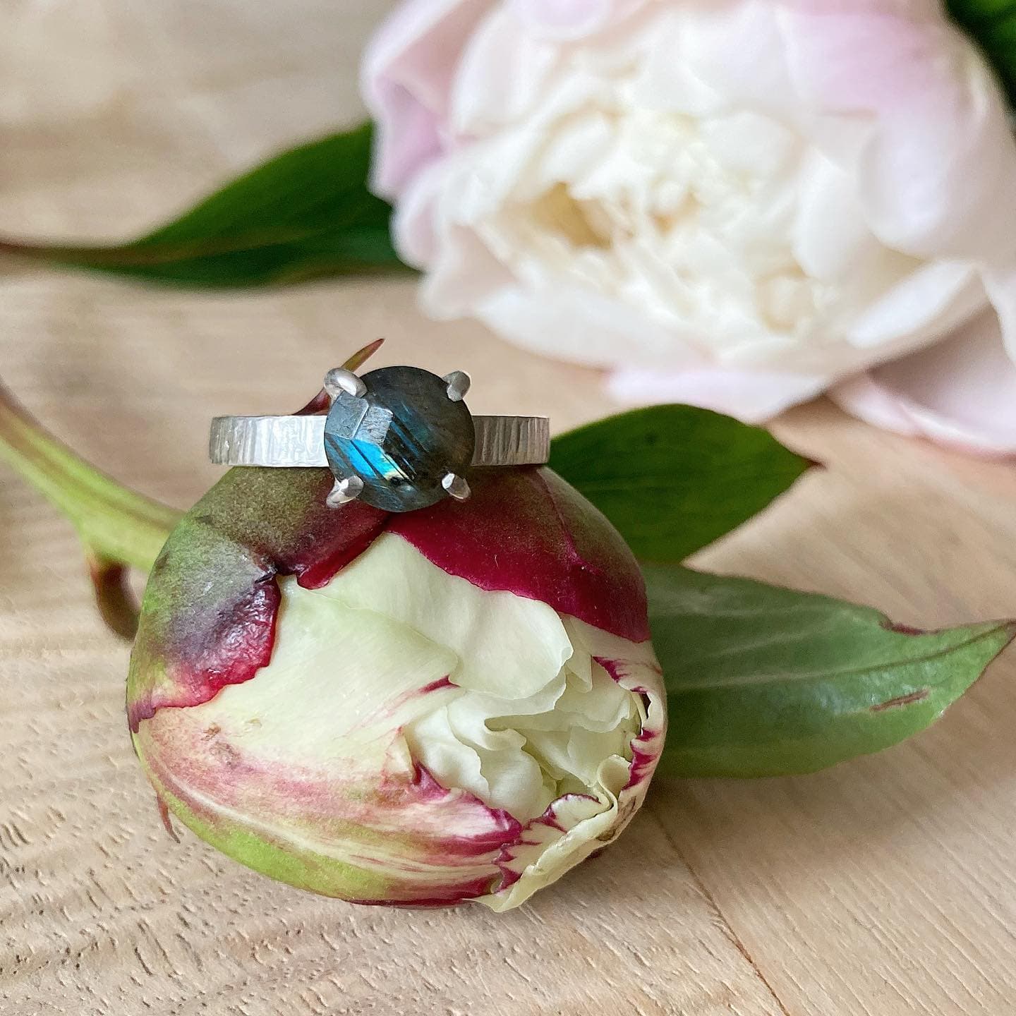 Gouden ring naast witte pioenroos