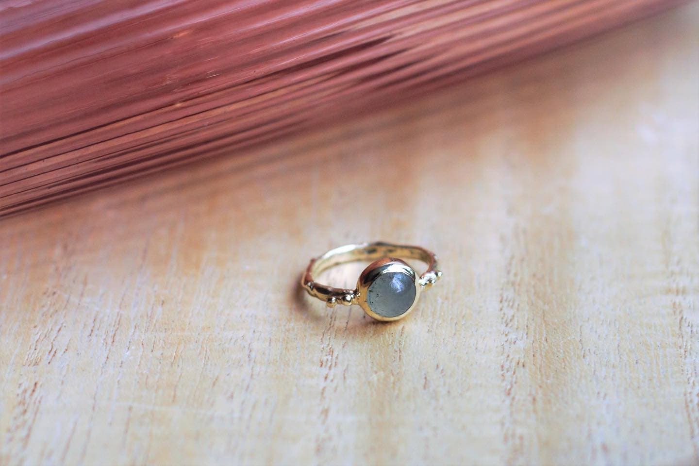 Gouden ring met kleine blauwe steen op lichte ondergrond