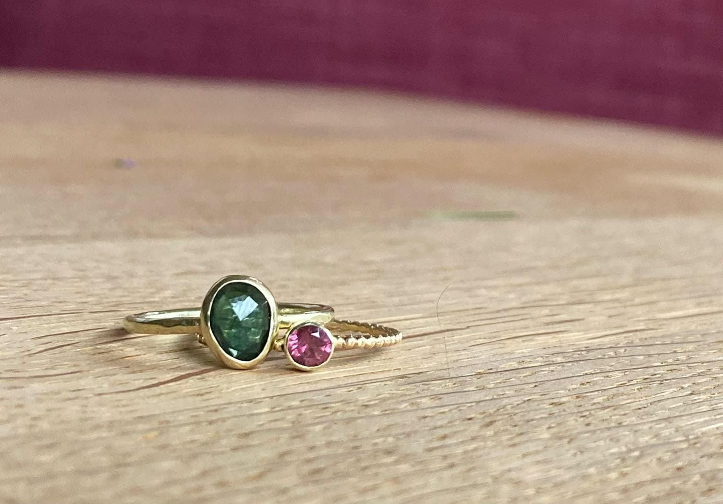 Gouden ring met ronde donkere steen op paars-rode ondergrond