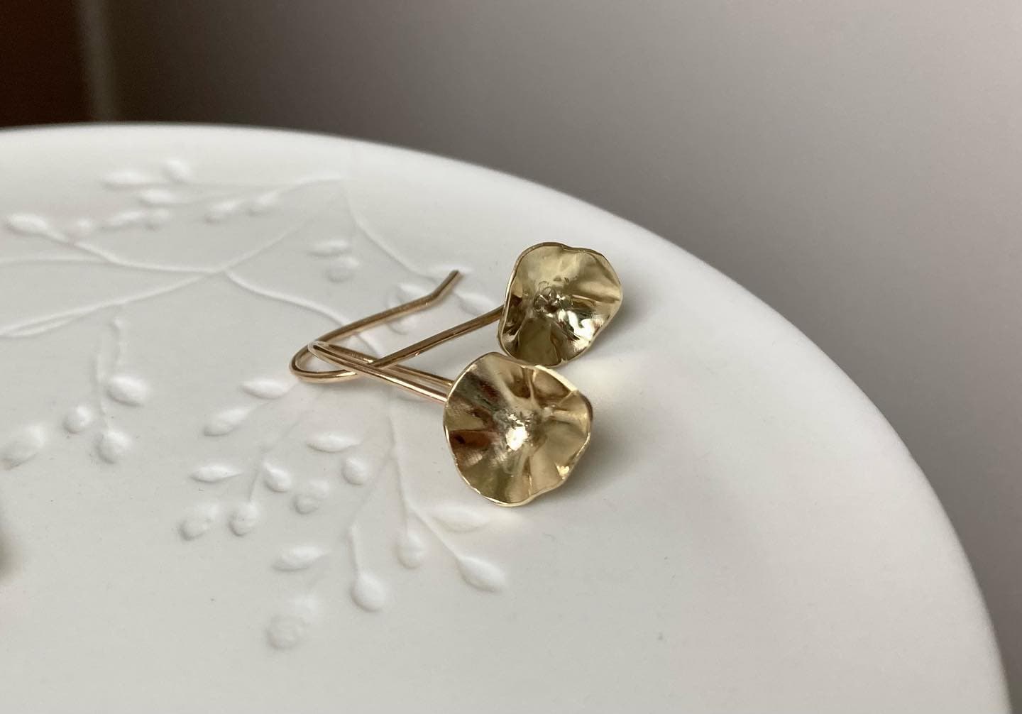 Gouden hartvormige oorbellen op wit schaaltje