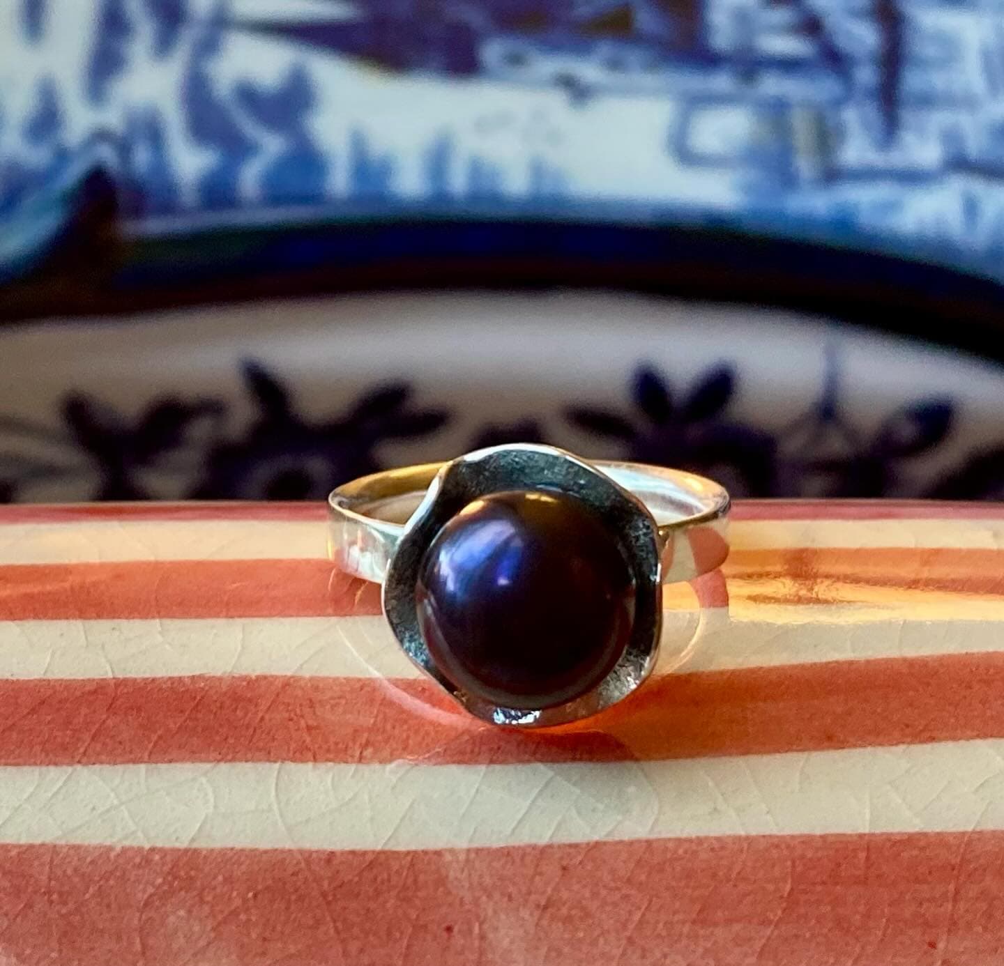 Gouden ring met grote donkerrode steen op gestreepte ondergrond