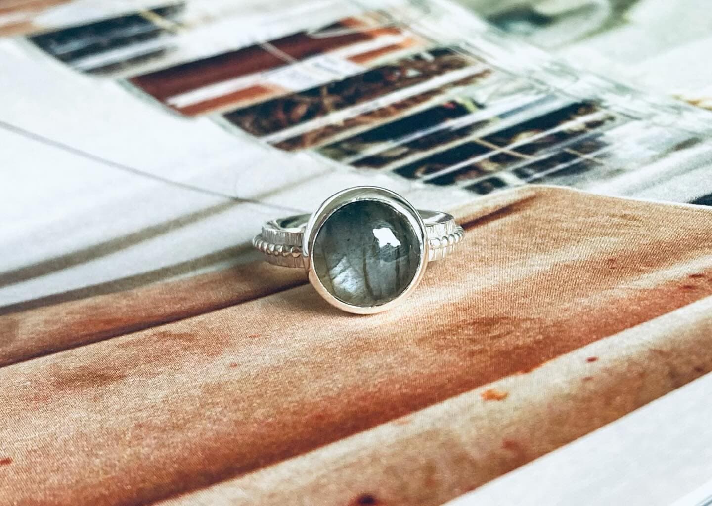 Gouden ring met donkere steen (mogelijk labradoriet) op marmer