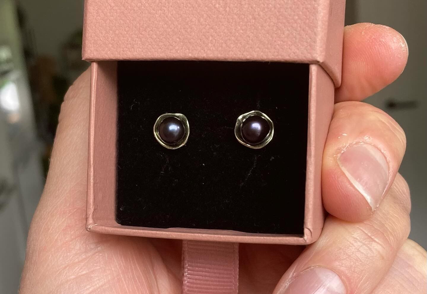 Donkerblauwe steen-oorbellen close-up in zwart doosje op hand
