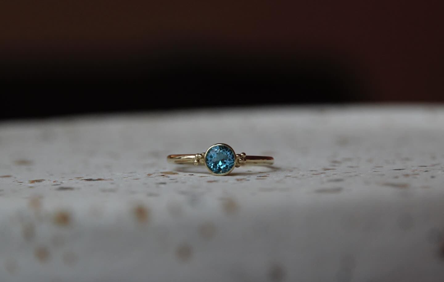 Gouden ring met klein steentje op grijze ondergrond