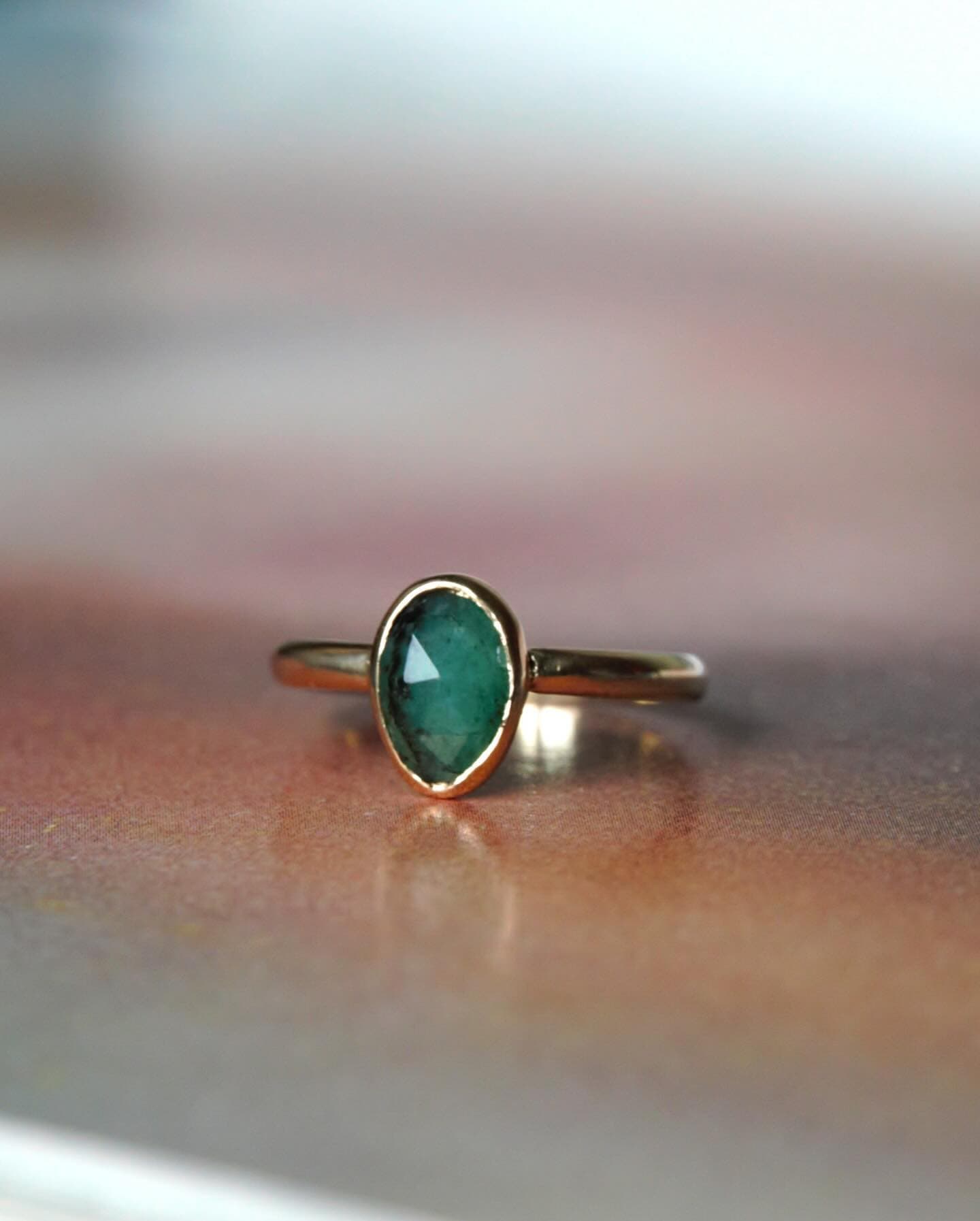Gouden ring met groene steen op tafel, soft-focus
