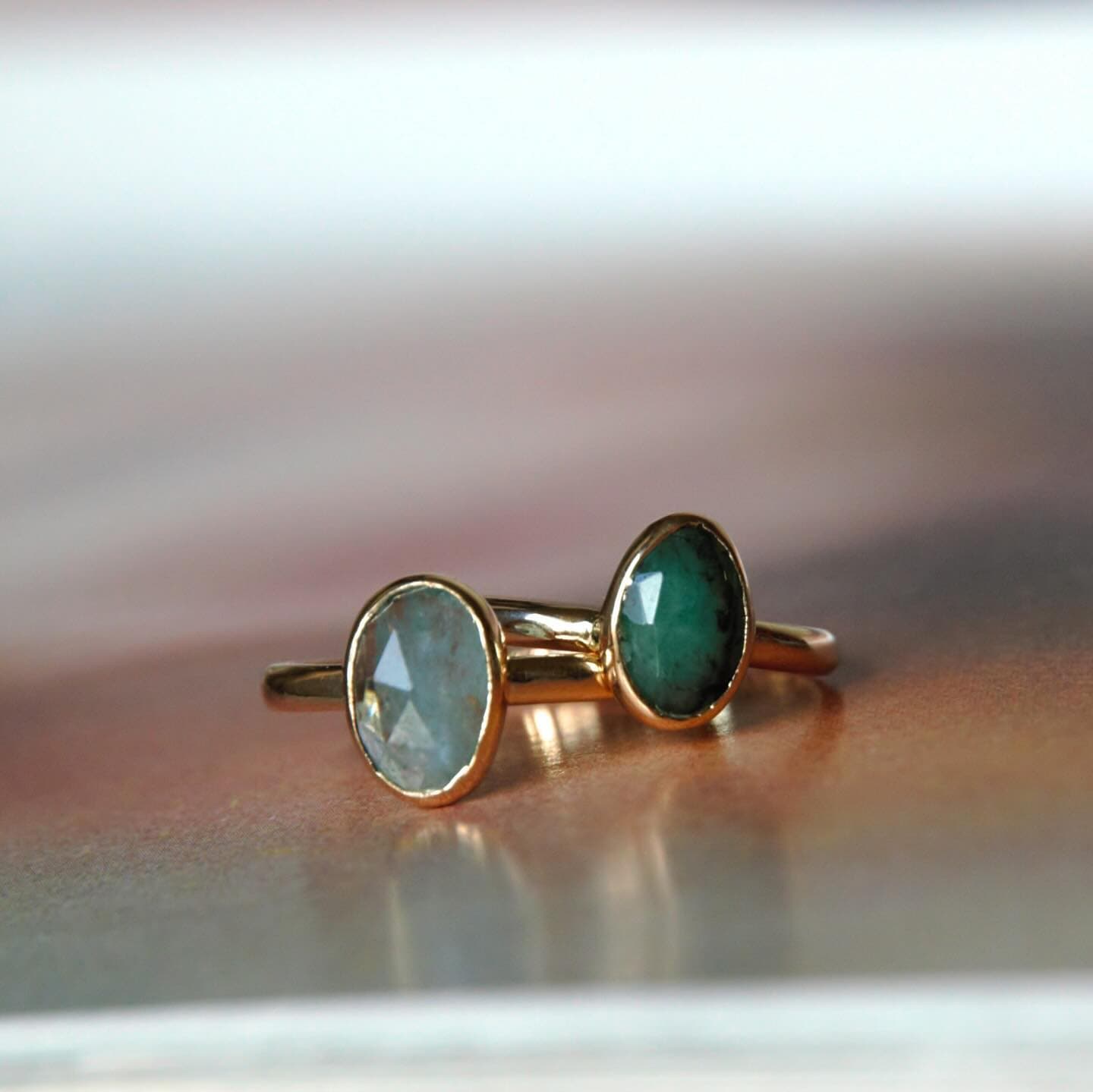 Gouden ring met ovale groene facetsteen op grijze ondergrond