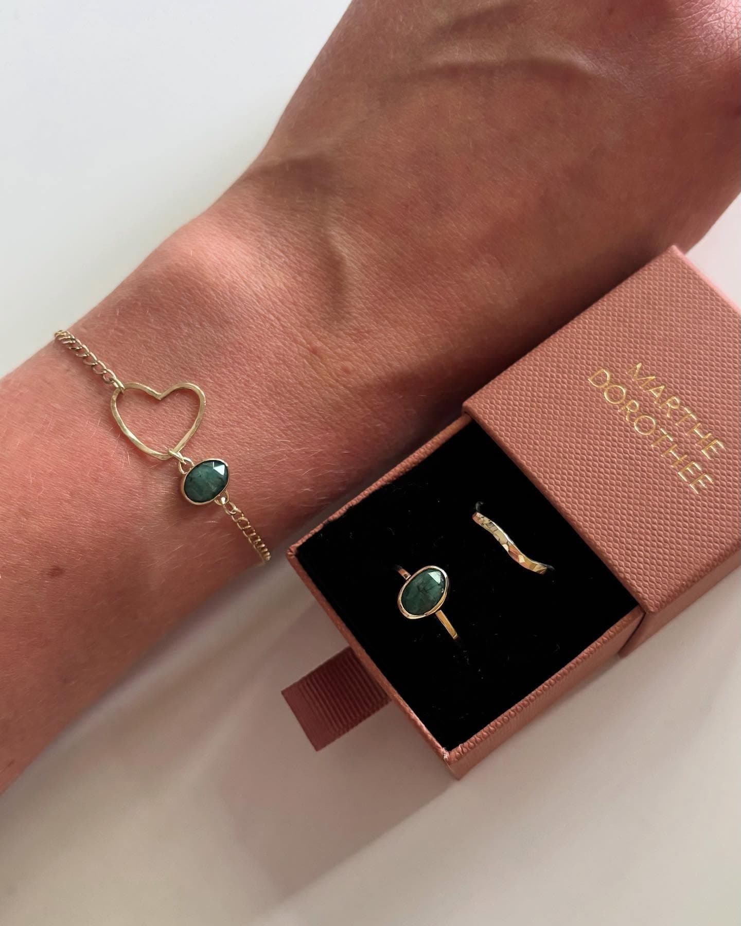 Arm met fijne gouden armband en ring bij sieradendoosje