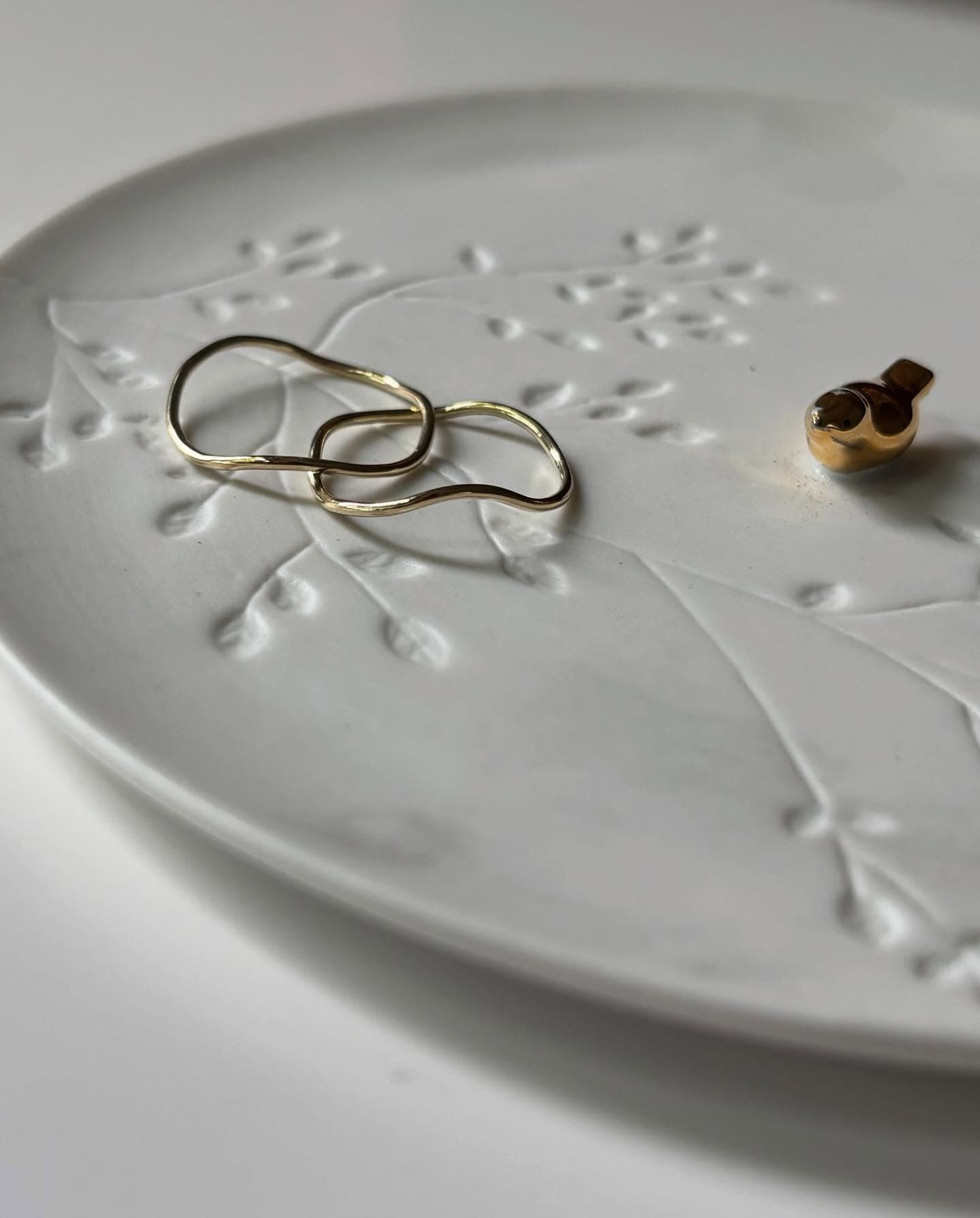 Twee paar kleine oorbellen op witte schaal met bloemmotief