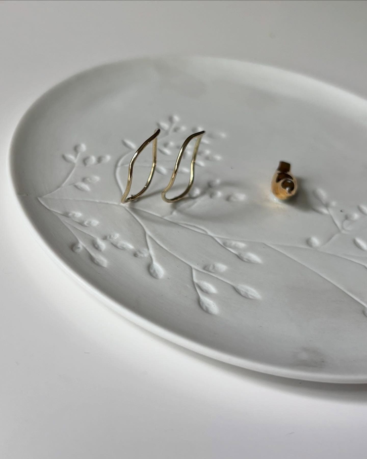 Twee paar oorbellen op witte schaal met bloempatroon