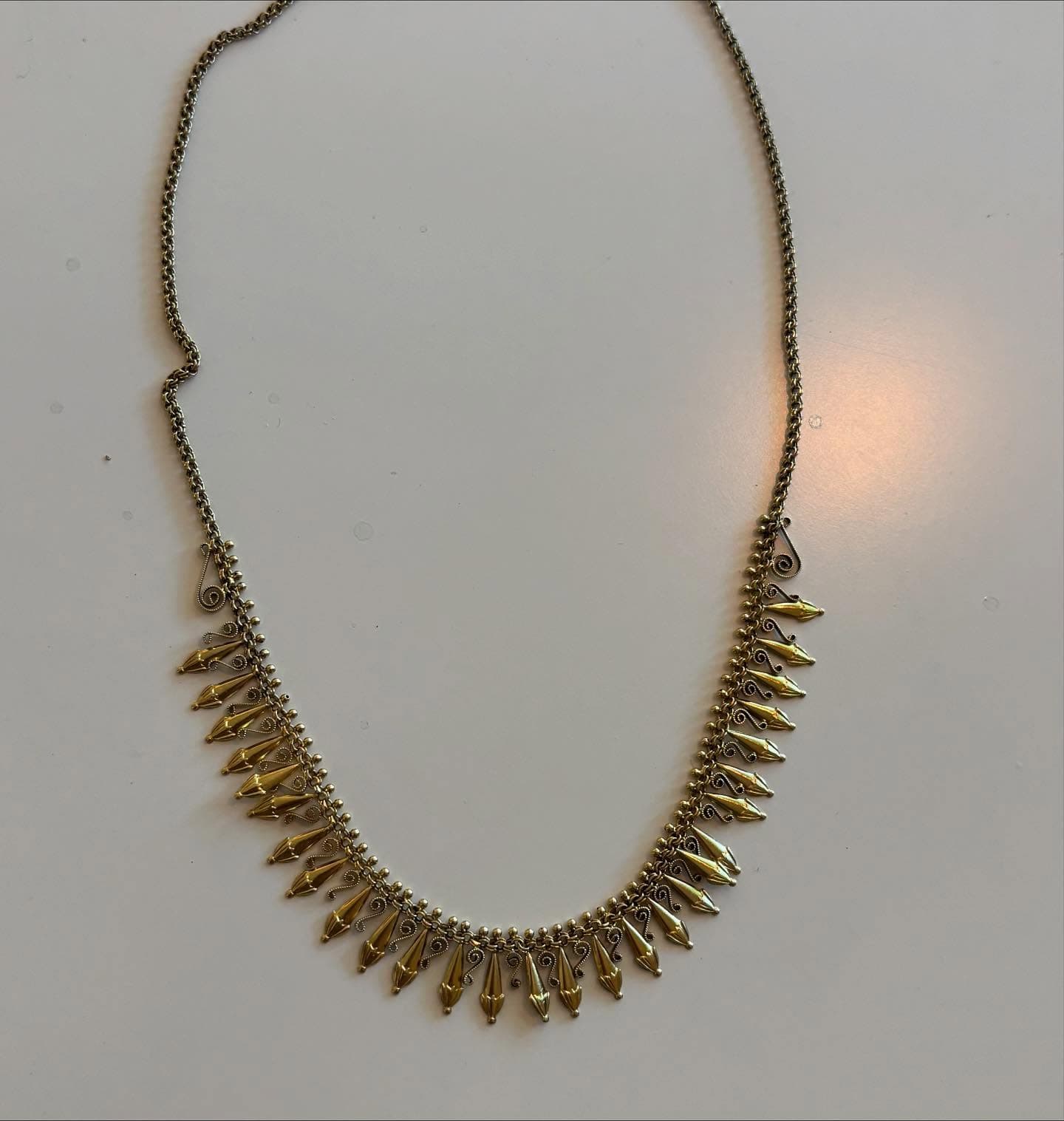 Lange gouden halsketting met kraalhanger op tafel