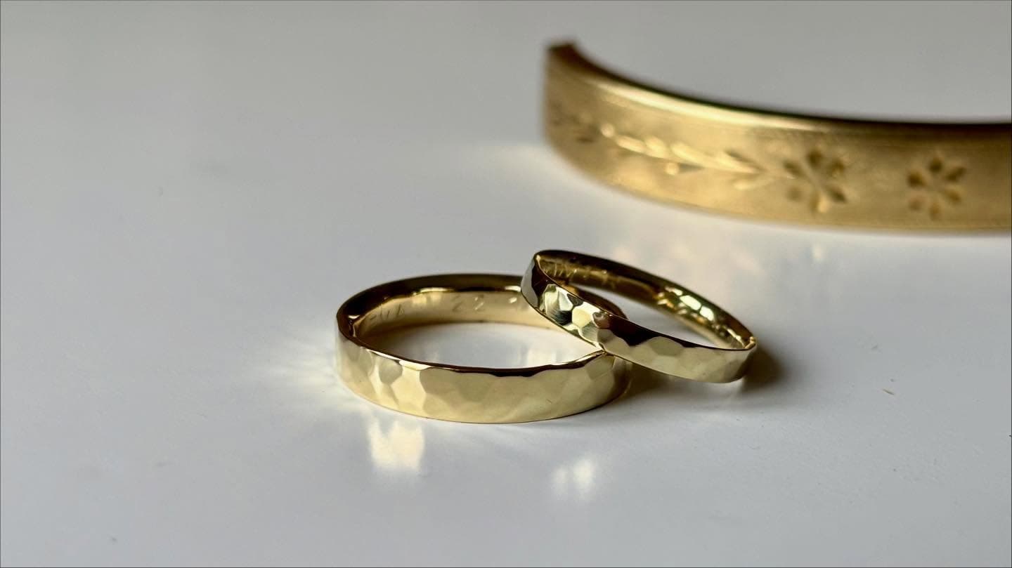 Twee gouden trouwringen: één met hamerslagtextuur en één met kleine steen