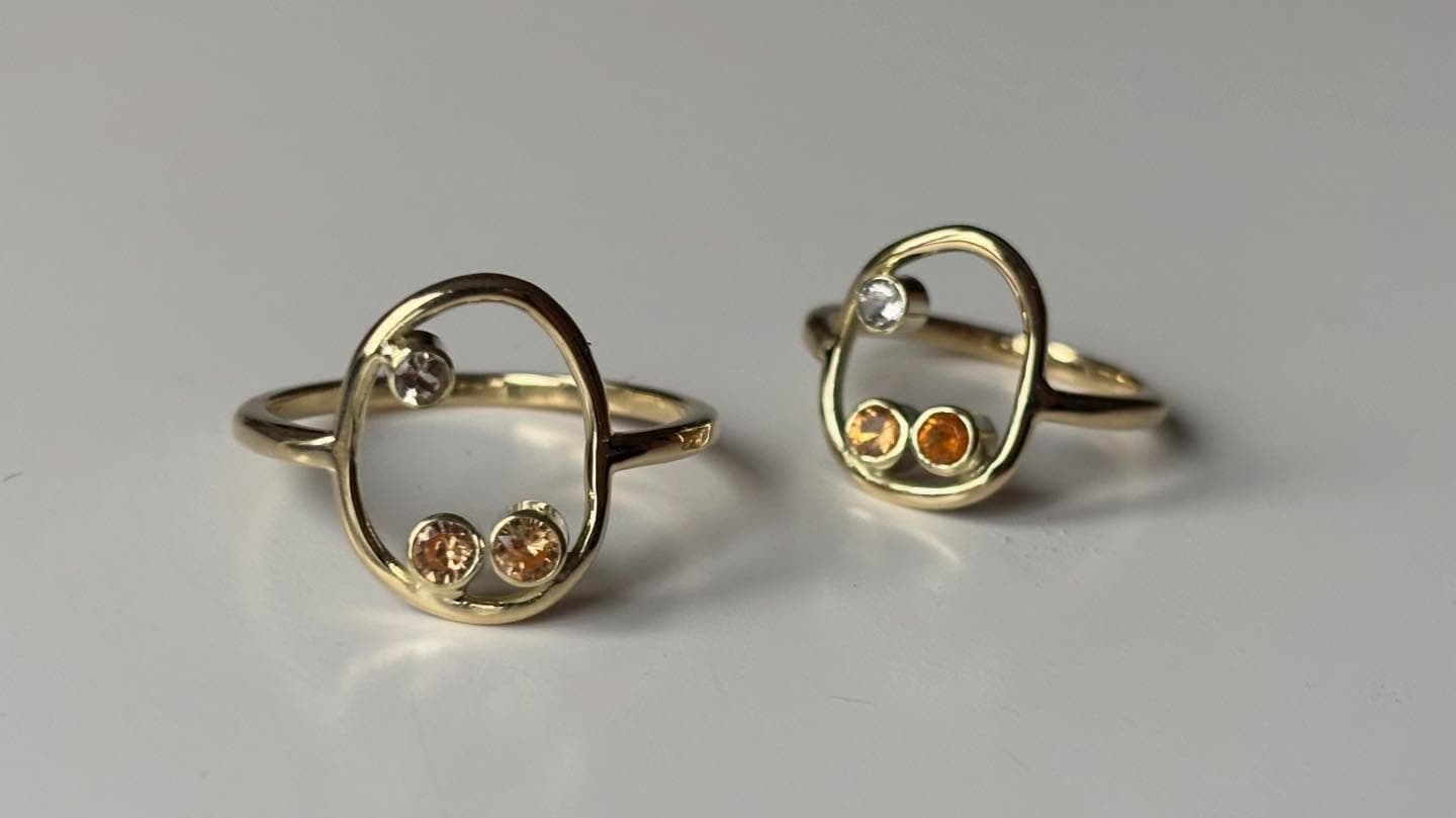 Twee gouden open ringen zij aan zij met kleine facetsteentjes