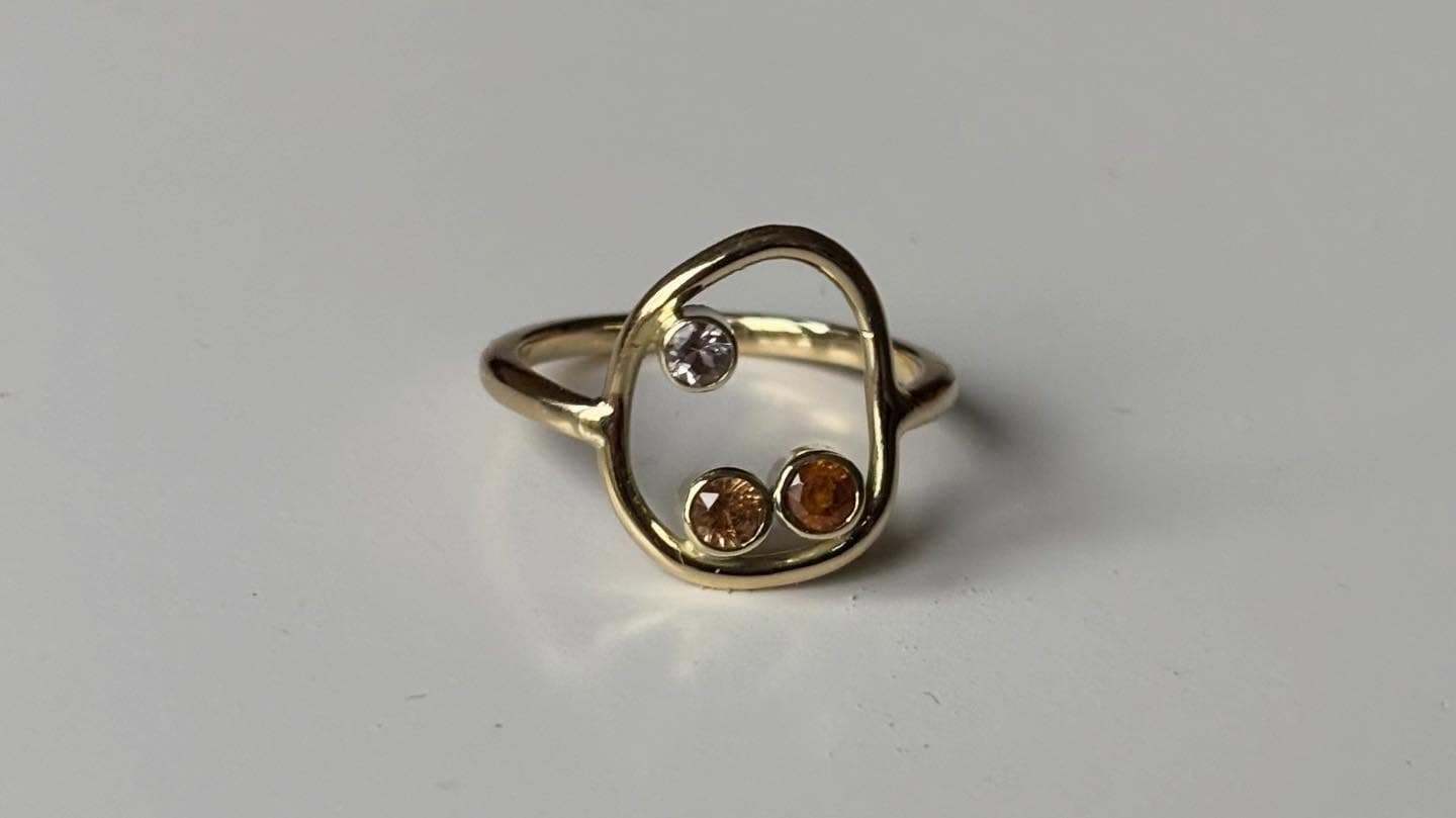 Open gouden ring met klein facetsteentje op tafel