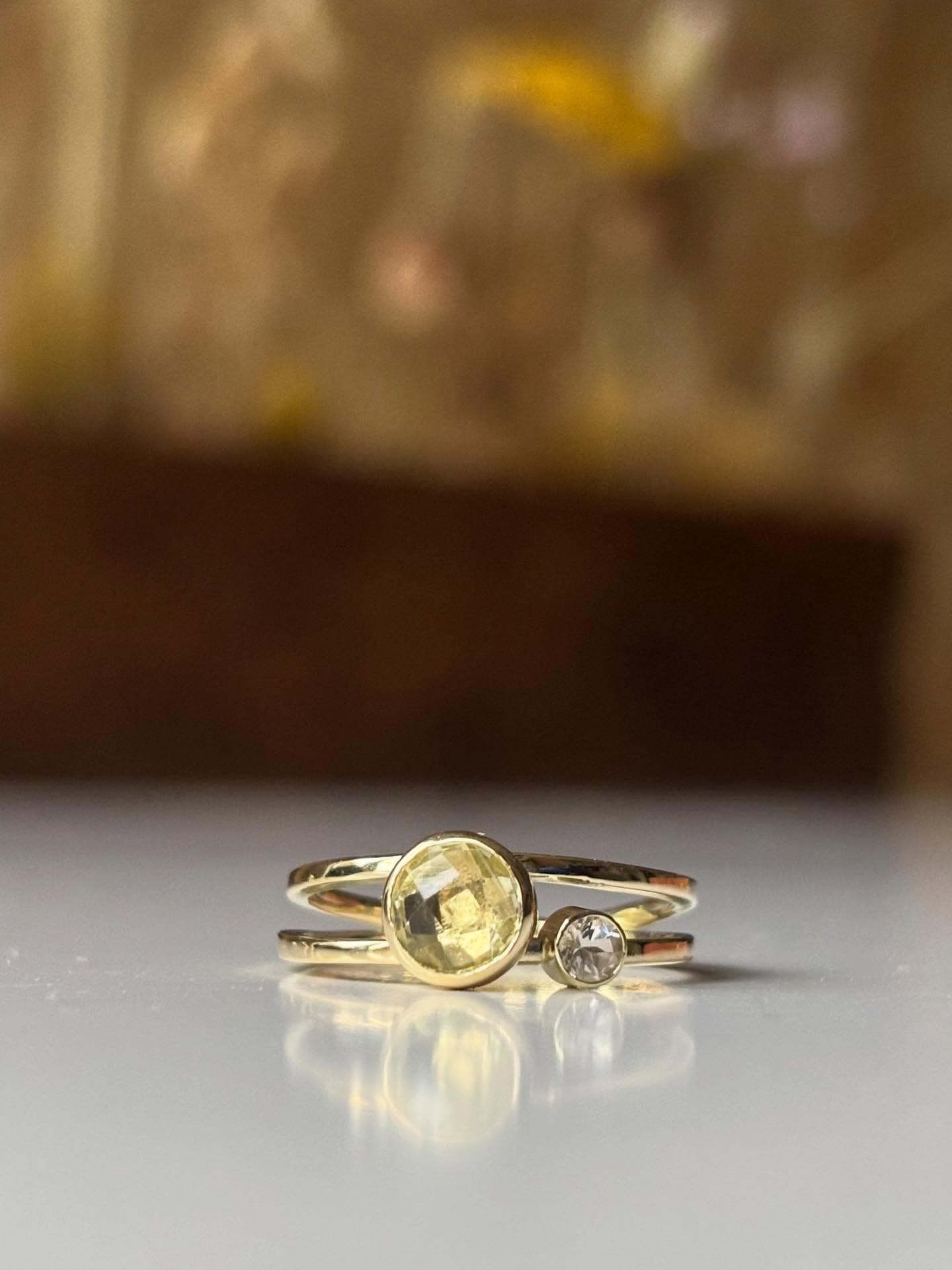 Gouden ring met ronde gele facetsteen op bloemenachtergrond