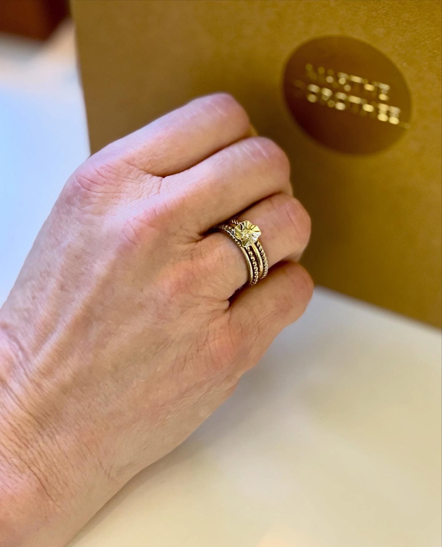 Hand met brede gouden ring bij goudkleurig accessoire