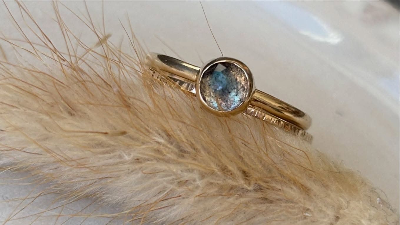 Gouden ring met ronde blauwe facetsteen (blauwe topaas) op veren